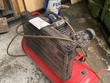 a red air compressor sitting on the floor next to a pile of wood