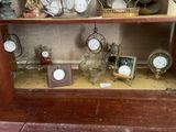 une étagère sur laquelle sont disposées de nombreuses horloges et photos différentes