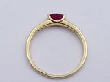 a close up of a gold ring with a red stone