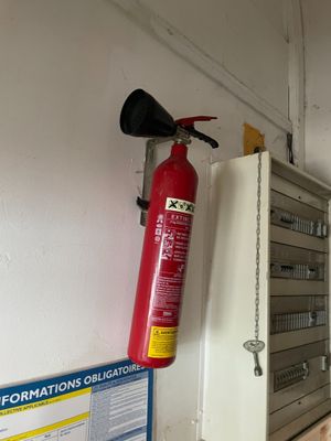 un extincteur accroché au mur à côté d'une borne d'incendie