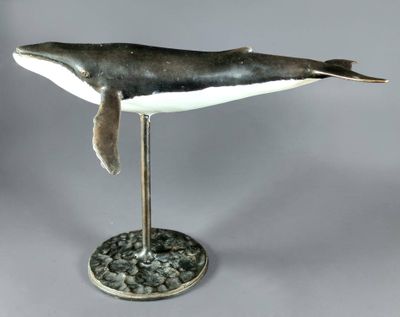 statue of a humpback whale sitting on a rock base
