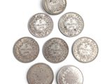 six types différents de pièces d'argent sur une surface blanche