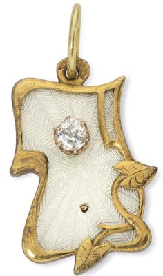 a close up of a gold and white pendant with a diamond