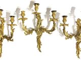 three gold colored metal wall sconces with candles on each of them