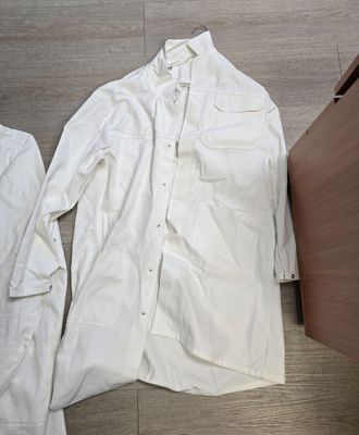 une chemise blanche posée par terre à côté d'une armoire en bois