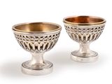 pair of silver and gold footed cups on pedestals on a white background