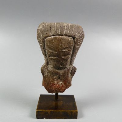 a close up of a statue of a head on a wooden stand