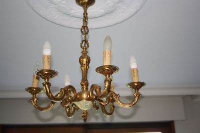 a gold chandelier with five lights hanging from the ceiling