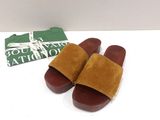 brown sued slippers with brown soles on a white surface