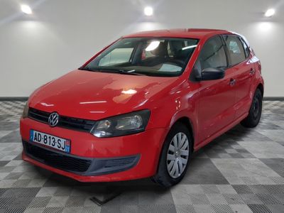 La Volkswagen Polo rouge est garée sur un sol carrelé à damier.