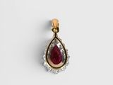 a close up of a pendant with a red stone in it