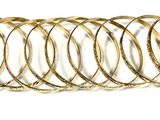 une pile de bracelets en or posée sur une surface blanche