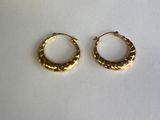 deux petites boucles d'oreilles en or en forme d'anneau sur une surface blanche