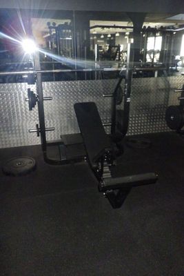 une salle de sport équipée d'un banc, d'haltères et d'autres appareils