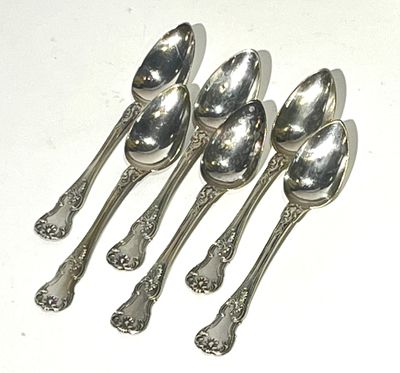 six silver spoons are lined up on a white surface