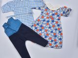une photo d'un ensemble de vêtements pour bébé posé sur une surface blanche