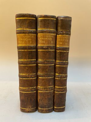 trois vieux livres empilés sur une surface blanche