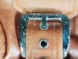 a close up of a brown leather bag with a metal buckle