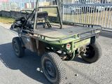 un petit utilitaire vert garé sur le bord de la route