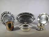 trois plats en argent et une coupe en argent posés sur une table