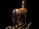 an old wooden rocking horse with a long mane on a black background