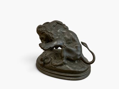 bronze statue of a lion on a rock with a mouse in its mouth