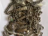 a pile of silver jewelry on a white surface