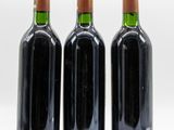 three bottles of wine are lined up on a white surface