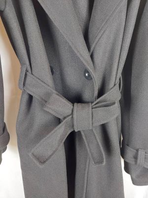Le manteau est gris et comporte un grand nœud sur le devant
