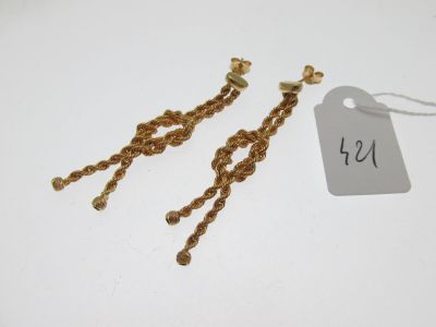 une paire de boucles d'oreilles en or avec une étiquette de prix sur fond blanc