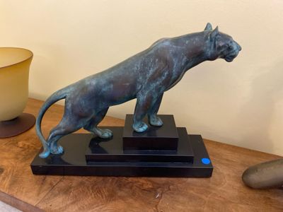 a statue of a cat on a table next to a bowl