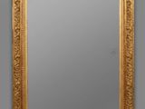 a gold framed mirror on a wall with a gray background