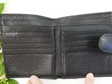 someone is holding a black leather wallet with a button on it