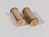 two gold bullet shells on a white surface