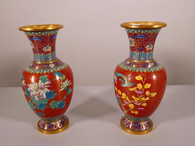 une paire de vases rouges ornés de motifs floraux, posés sur une table