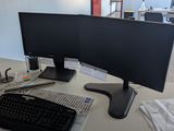 a computer desk with two monitors and a keyboard on it