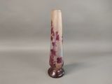 a tall glass vase with a purple flower design on it