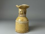 un vase jaune surmonté d'un oiseau
