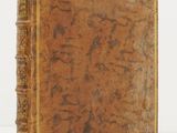 an old book sitting on top of a table next to a white wall