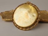 an image of a gold broochle with a woman ' s face in the center