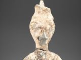 une main tenant une petite statue en pierre représentant une personne