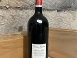 a bottle of red wine sitting on a wooden shelf
