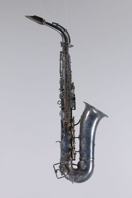 an old saxophone hanging from a string on a wall