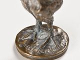 statue of a chicken on top of a coin on a white surface