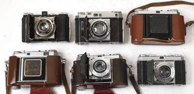 plusieurs vieux appareils photo sont alignés sur une surface blanche