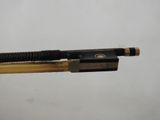 someone is holding a wooden stick with a black and gold bow on it