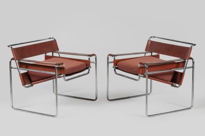 a pair of brown leather chairs with chrome frame legs