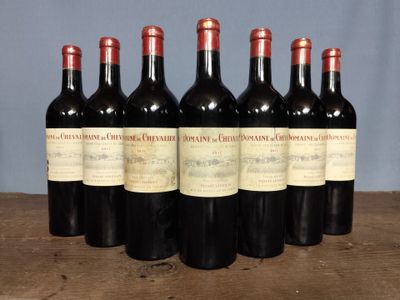 six bottles of red wine are lined up on a wooden table
