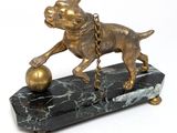 bronze statue of a dog with a ball on a marble base