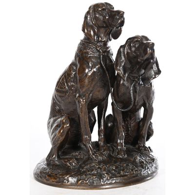statue en bronze représentant deux chiens assis l'un à côté de l'autre sur une surface blanche